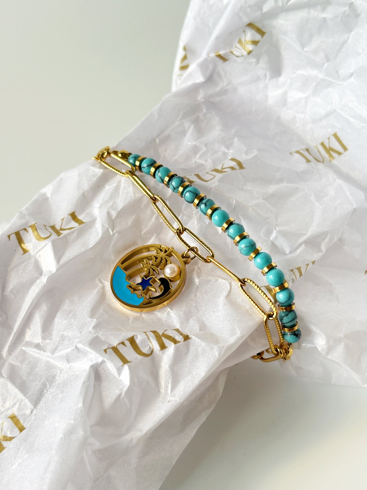 Turquoise beaded bracelet with gold accents on TUKI branded paper